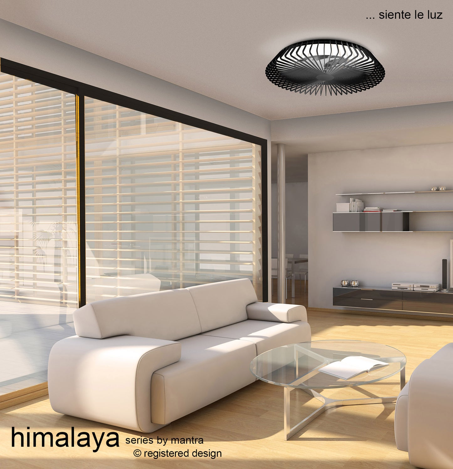 A modern living room with large windows featuring sheer blinds includes white sofas, a glass coffee table, and the Himalaya Black Ceiling Fan with Light from Ceiling Fans UK. A floating shelf adorns the wall, while the Alexa/Google Voice Control system enhances convenience. The setting is bright and minimalistic.