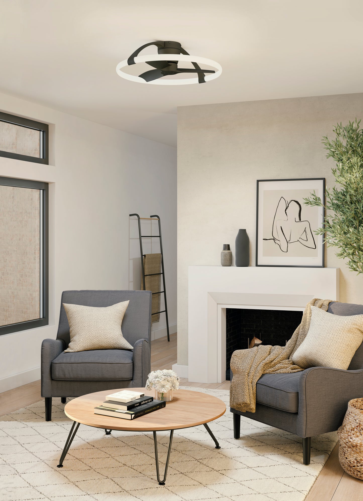A modern living room with two gray armchairs, a round wooden coffee table, and a minimalist fireplace is illuminated by the MANTRA M7802 Nepal Black Mini Ceiling Fan with 55W dimmable LED light from Ceiling Fans UK, offering remote & APP control for ambiance.
