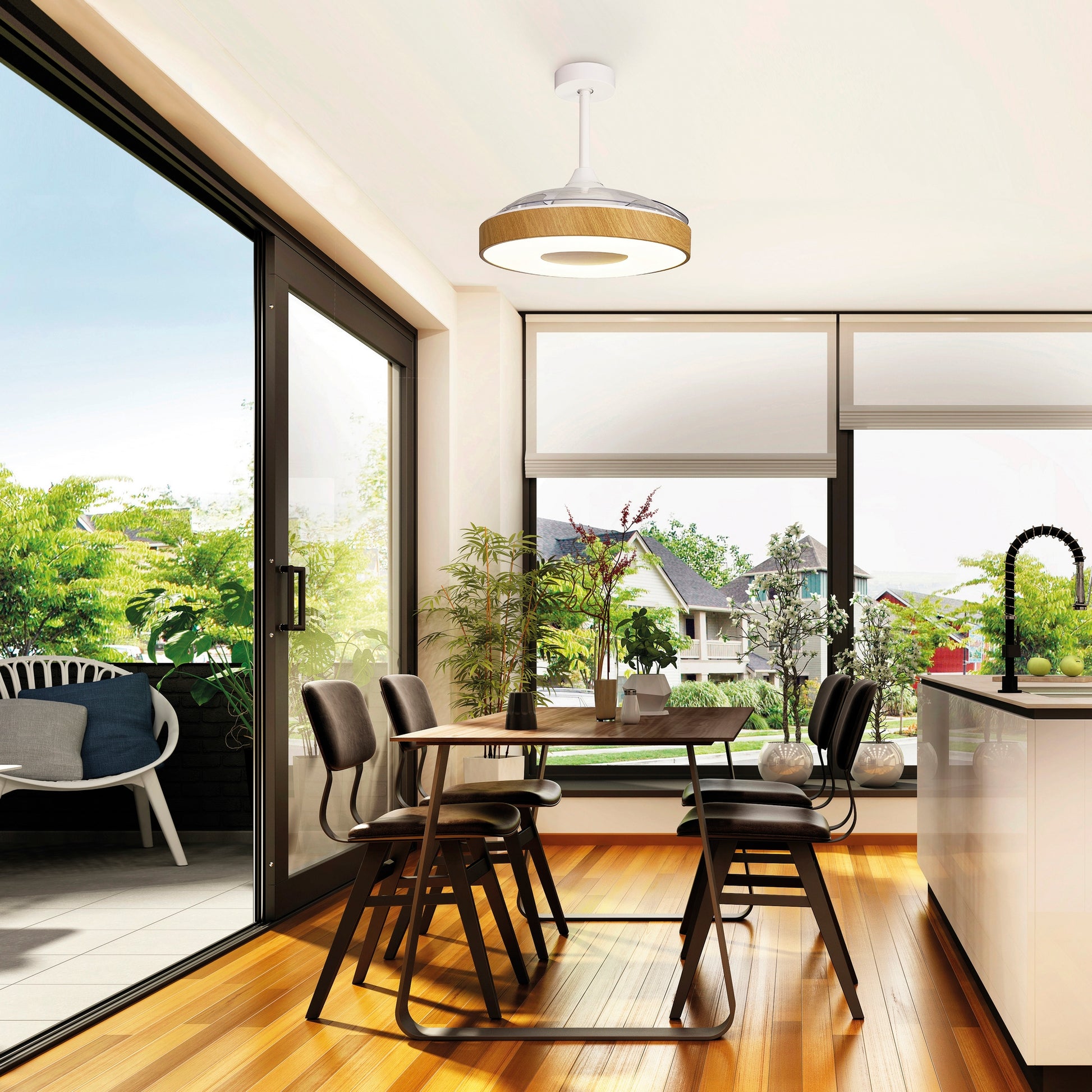 A modern dining area with a wooden floor features a table with four chairs. Large glass doors and windows offer a view of a green outdoor space with a seating area. A sleek pendant light hangs from the ceiling, complemented by the Coin White/Wood Ceiling Fan with light 60W LED Dimmable Ceiling Light With Built-In 30W DC Reversible Fan, Remote & APP Control from Ceiling Fans UK, which has a 5-year warranty. A kitchen counter with a black faucet is visible on the right.