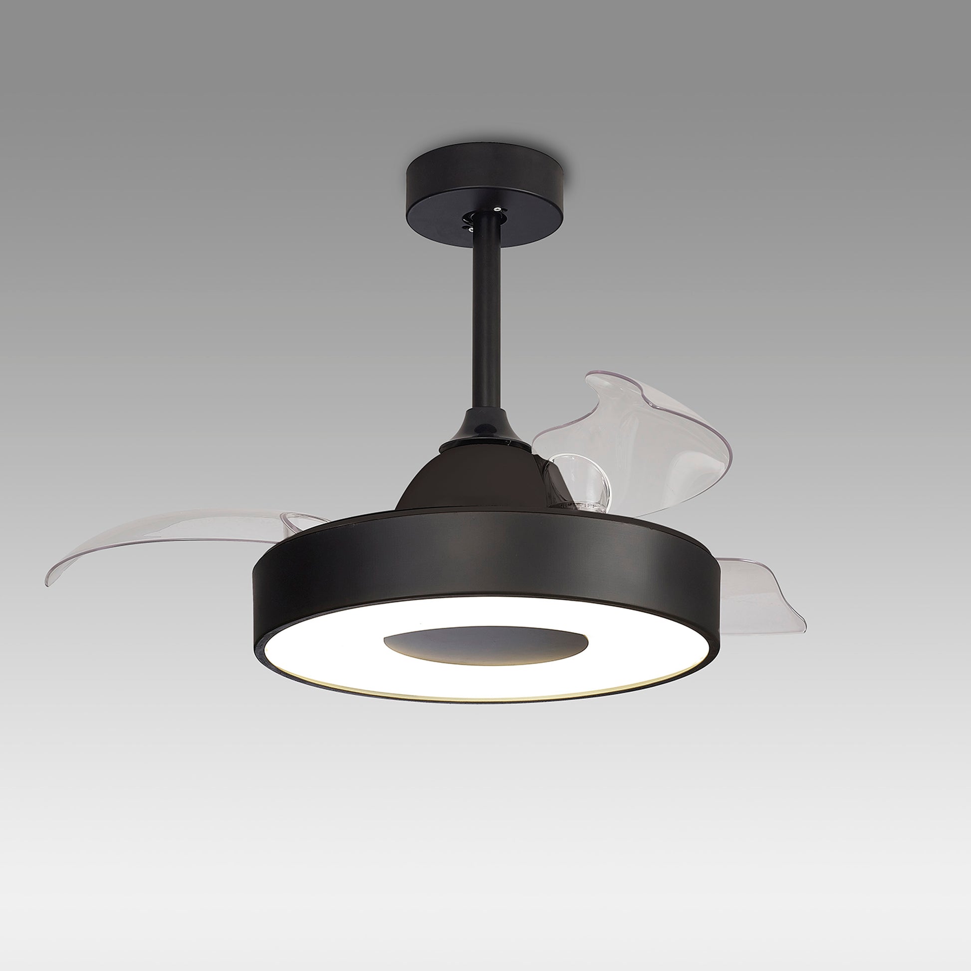 The Coin Black Ceiling Fan by Ceiling Fans UK is a modern fixture with translucent blades and a sleek black circular housing. This reversible fan hangs from the ceiling via a short black rod and features clear blades that enhance the central housing. The built-in 60W LED dimmable light brightens up any room, while the 30W DC reversible fan can be controlled via remote and app. It comes with a 5-year warranty, all set against a plain gradient gray background.