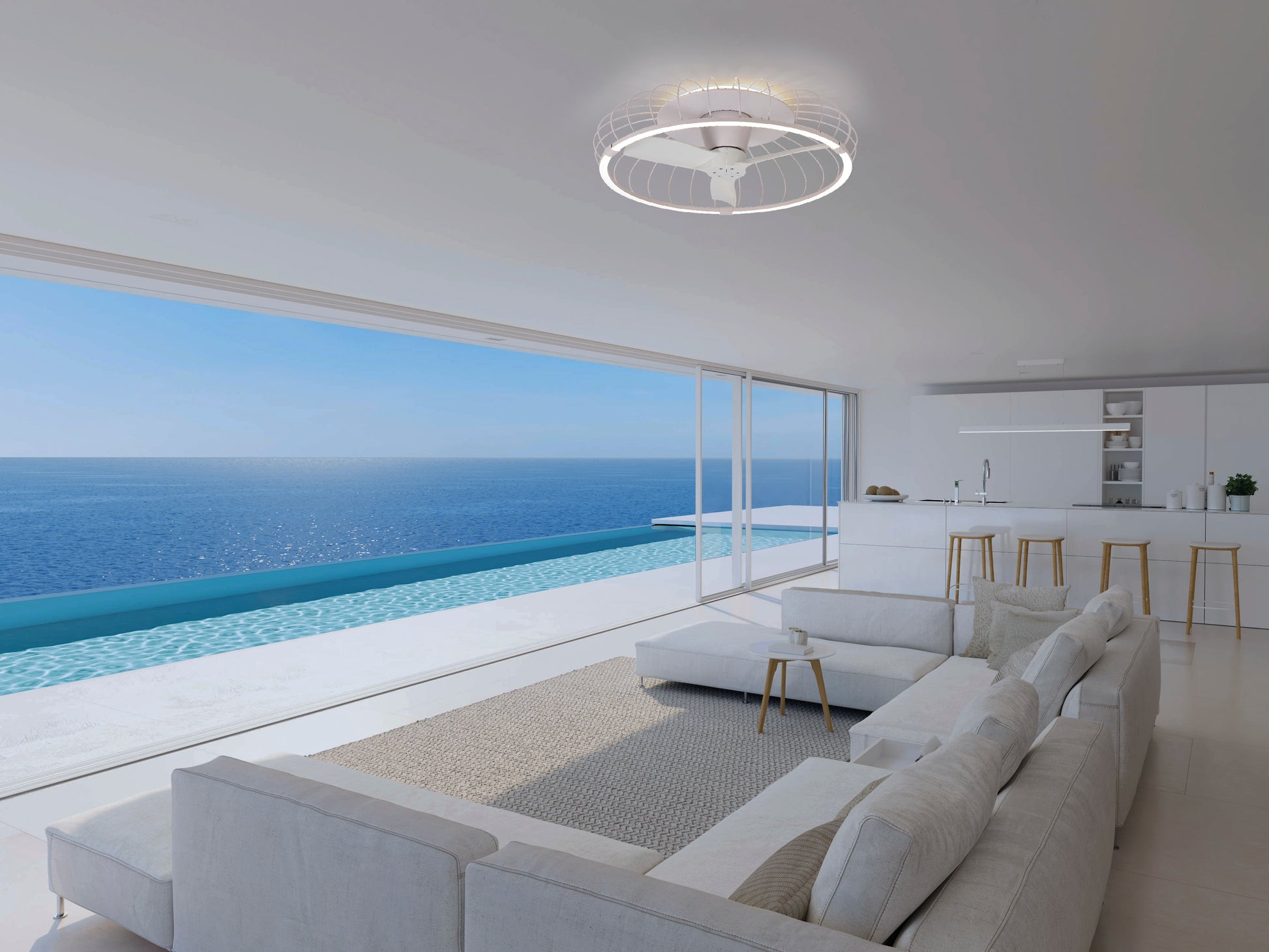 Modern living room with white furniture and open kitchen, featuring the MANTRA M7807 Nature White Ceiling Fan with 75W dimmable LED light, 30W reversible fan, remote & APP control by Ceiling Fans UK; floor-to-ceiling windows overlook an infinity pool and calm ocean.