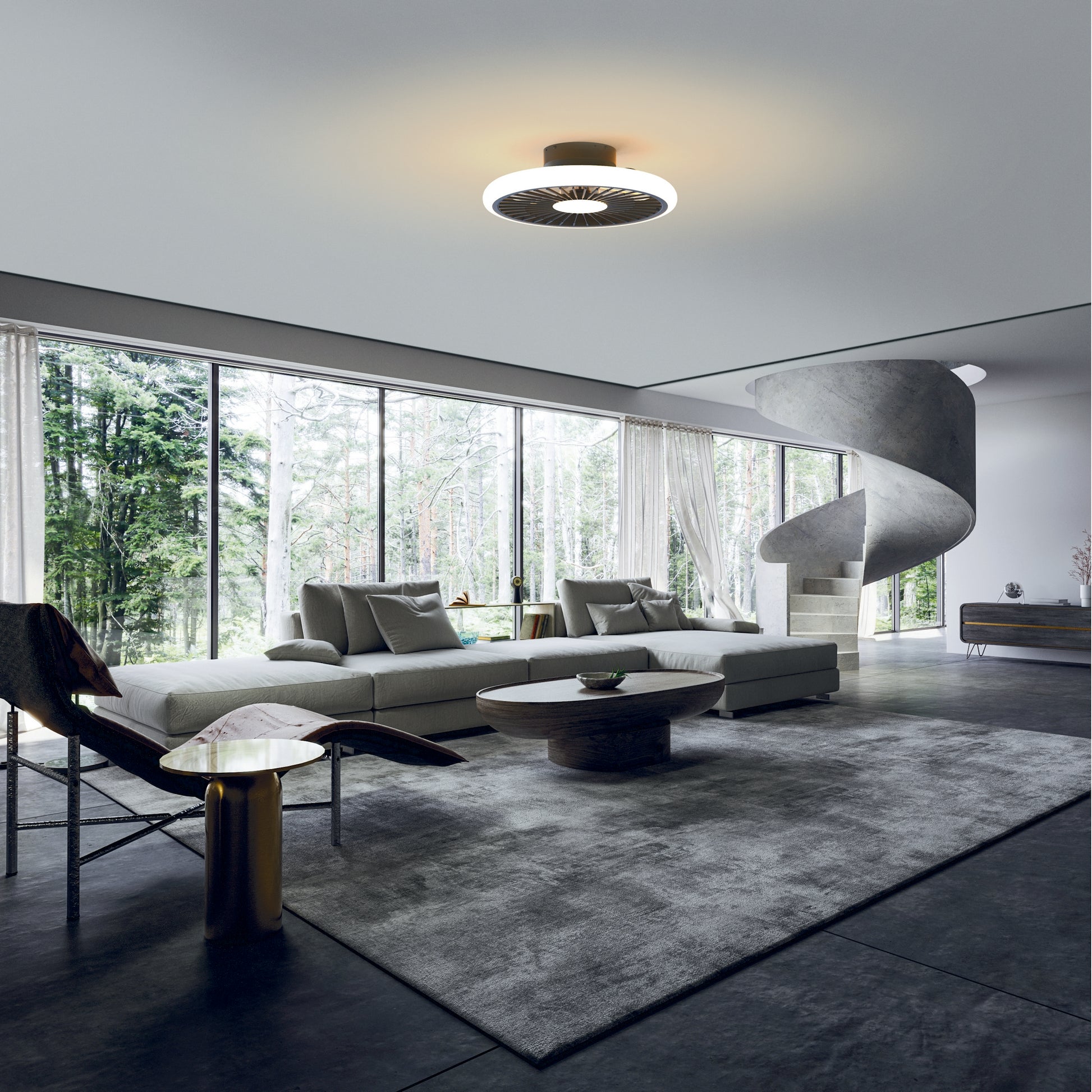 A modern living room featuring a large, sectional sofa with cushions, a round wooden coffee table, and a unique spiral staircase. Floor-to-ceiling windows allow natural light to flood in, offering a view of the surrounding greenery. The space is illuminated by the sleek Turbo Black Ceiling Fan with Light from Ceiling Fans UK, equipped with a 51.2cm 55W LED dimmable ceiling light and built-in 30W DC reversible fan, backed by a 5-year warranty.